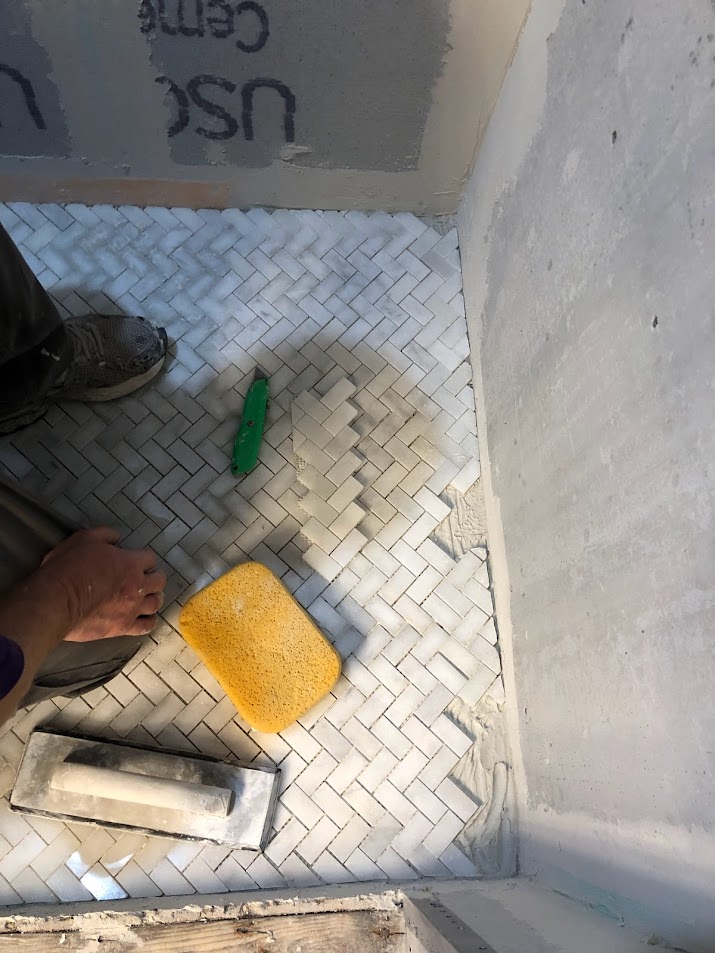 Herringbone marble mosaic floor going into our bathroom shower at the Georgian - Hello Lovely Studio.