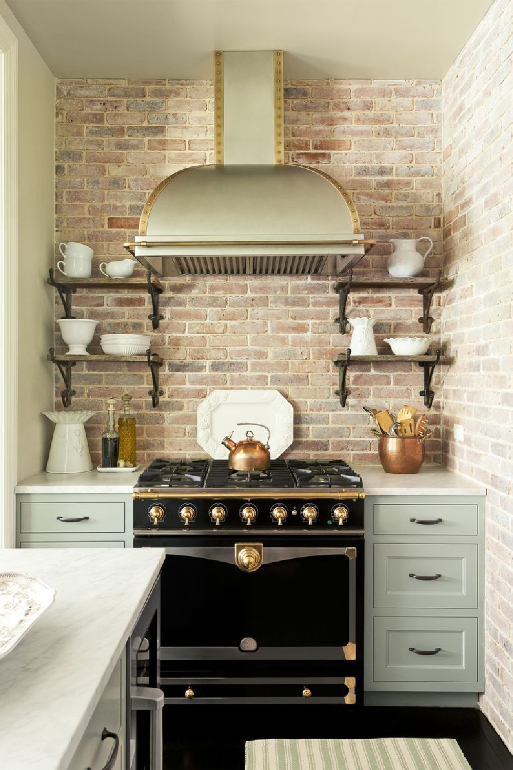 Country kitchen with black French range, brick backsplash and green-gray cabinets - photo by Emily Gilbert. #statementrange #countrykitchens