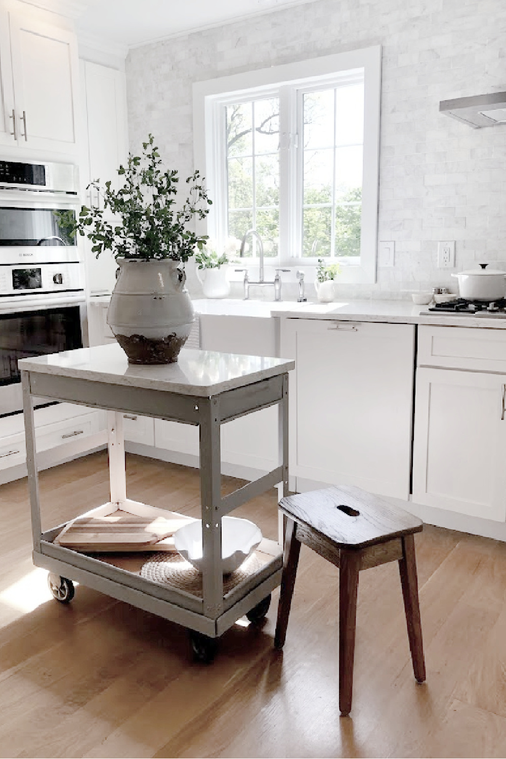 Modern French white kitchen with industrial vintage cart, Viatera Minuet quartz counters, and white oak floors - Hello Lovely Studio.