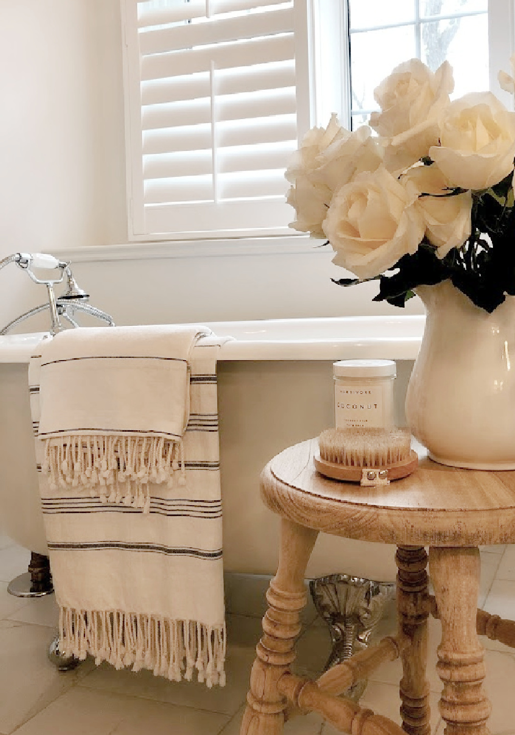 Modern French white bath with Turkish stripe towels, roses, and Herbivore coconut bath soak - Hello Lovely Studio.