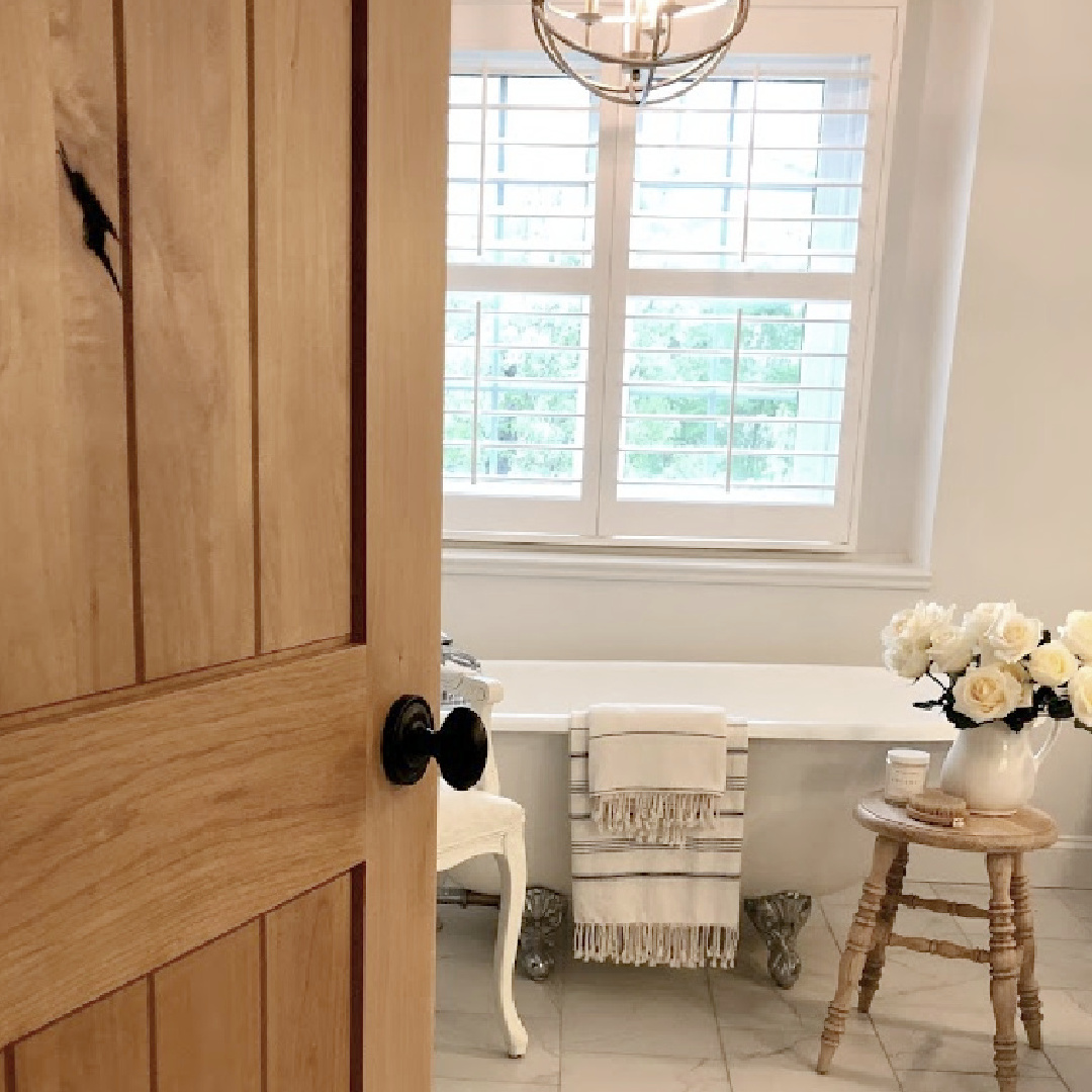 Knotty alder door to my modern French bath with vintage maid's tub and white everything - Hello Lovely Studio.