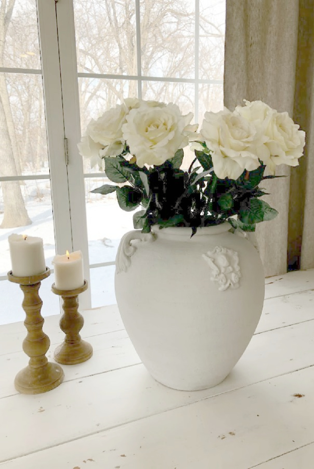 White roses in an old French terracotta pot on a white farm table in my modern French kitchen - Hello Lovely Studio.