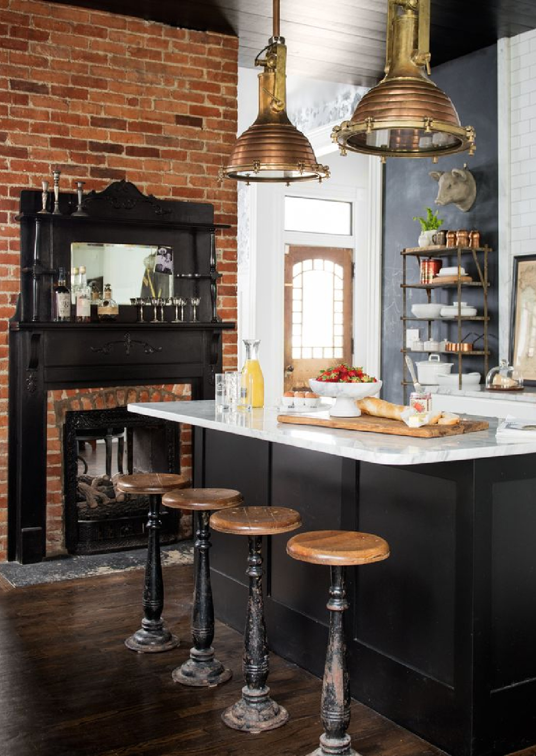 Black kitchen with red brick fireplace in a 1908 Nashville home by Holly Williams (photo: Paul Costello). #blackkitchens