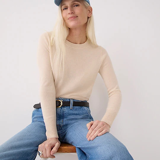 J. Crew model over 50 in a cashmere crewneck sweater, Point Sur pubble jeans, baseball cap, and black belt.