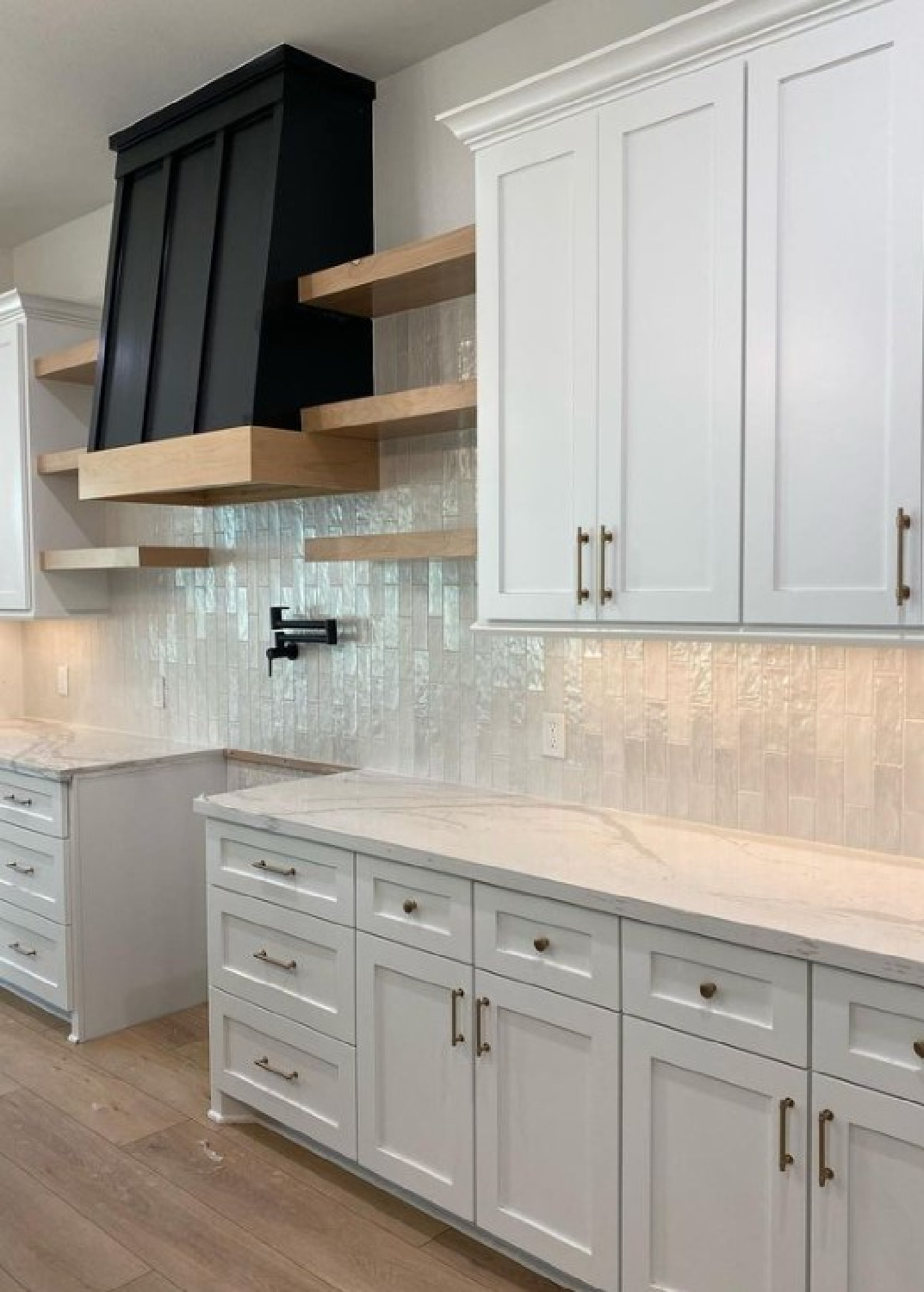 SW Snowbound in kitchen with Shaker cabinets, wood floating shelves, and black range hood - @wifeonadime. #swsnowbound