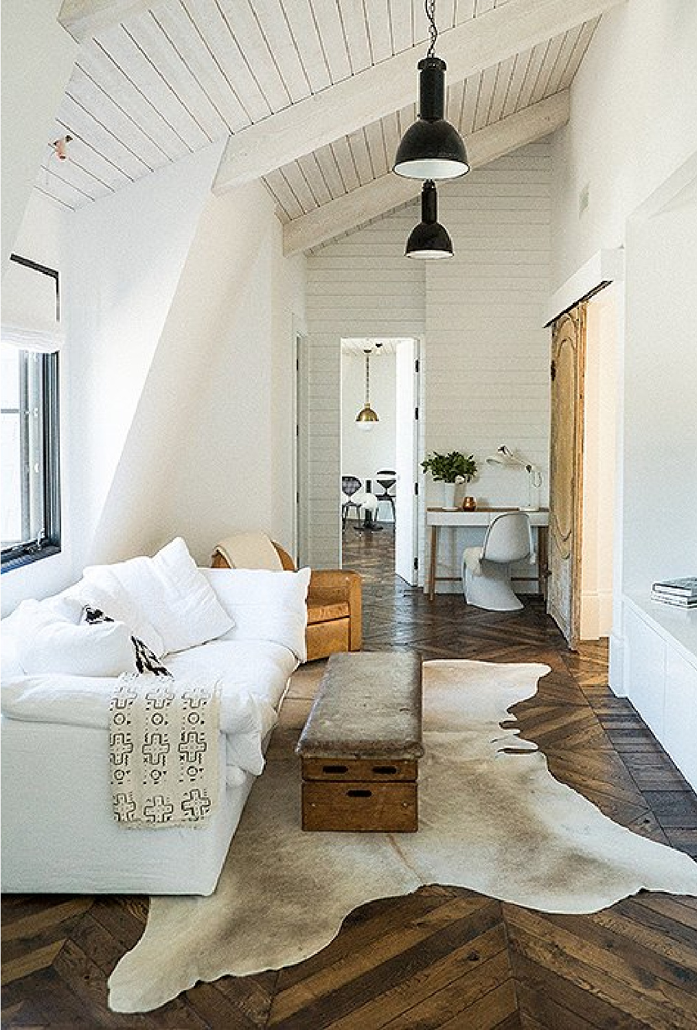 Leanne Ford rustic modern interior with cowhide, herringbone wood floor, white sofa, and barn door - photo by Josh Franer.