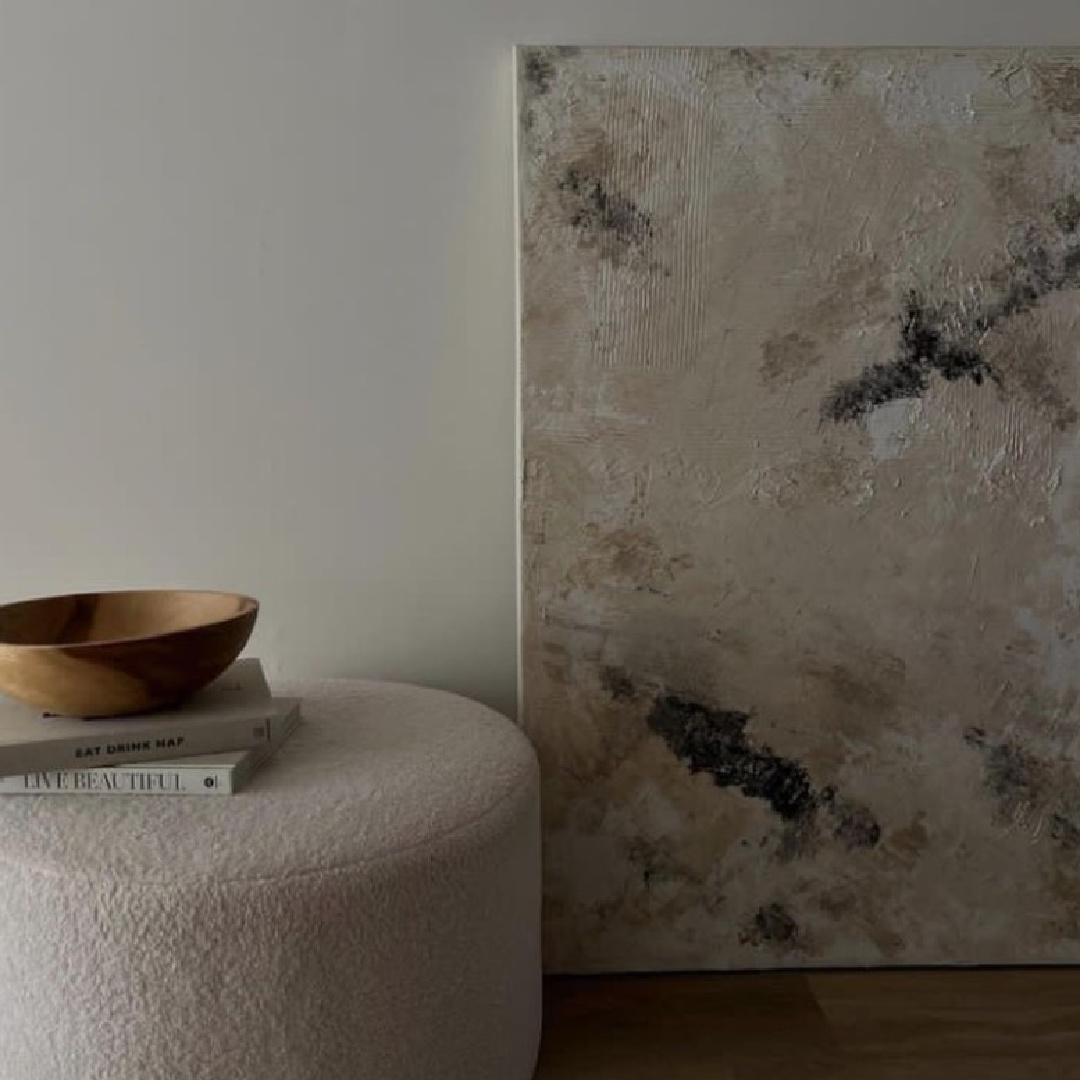 Greige vignette with large abstract painting and boucle ottoman - @stylemilaglow.