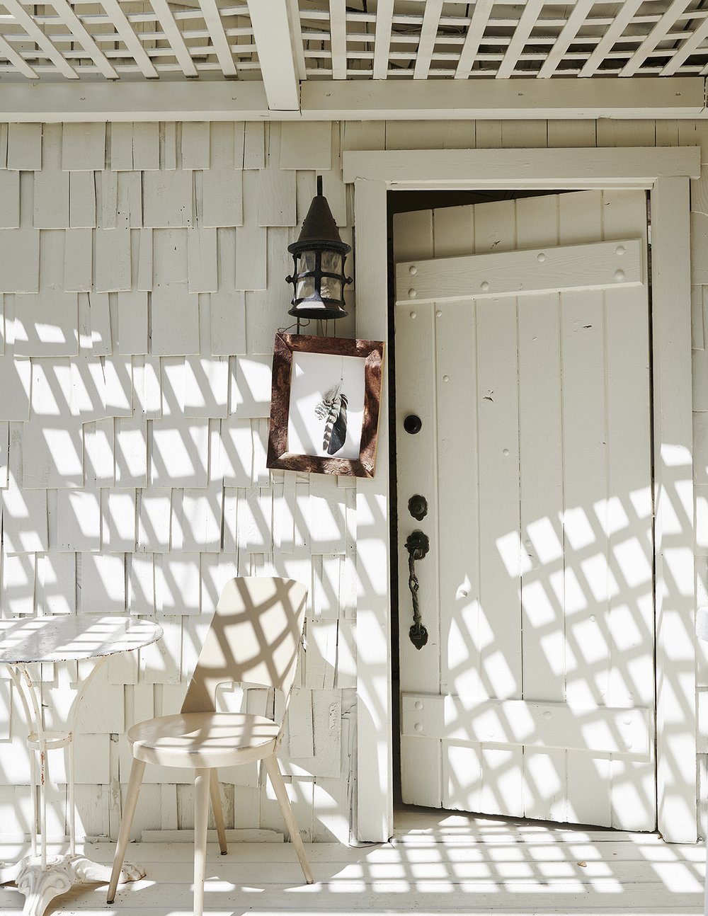 Dappled sunlight on a white California cottage with cedar shake and rustic door - Leanne Ford (photo by Amy Neunsinger).