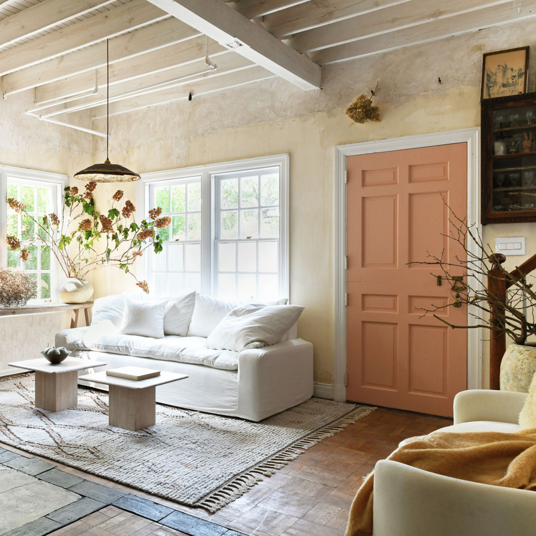 Leanne Ford designed cottage with peach door, rustic pieced together flooring, and slipcovered white sofa - photo by Erin Kelly.
