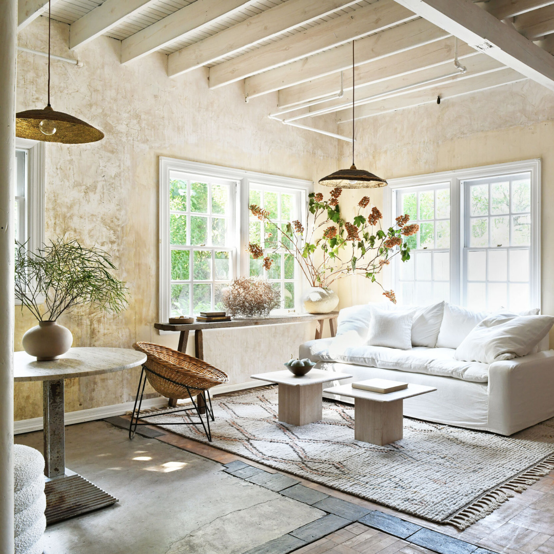 Leanne Ford designed living room with walls rubbed with coffee, a mix of pieced together flooring, white slipcovered sofa, and rustic organic modern style - photo by Erin Kelly.