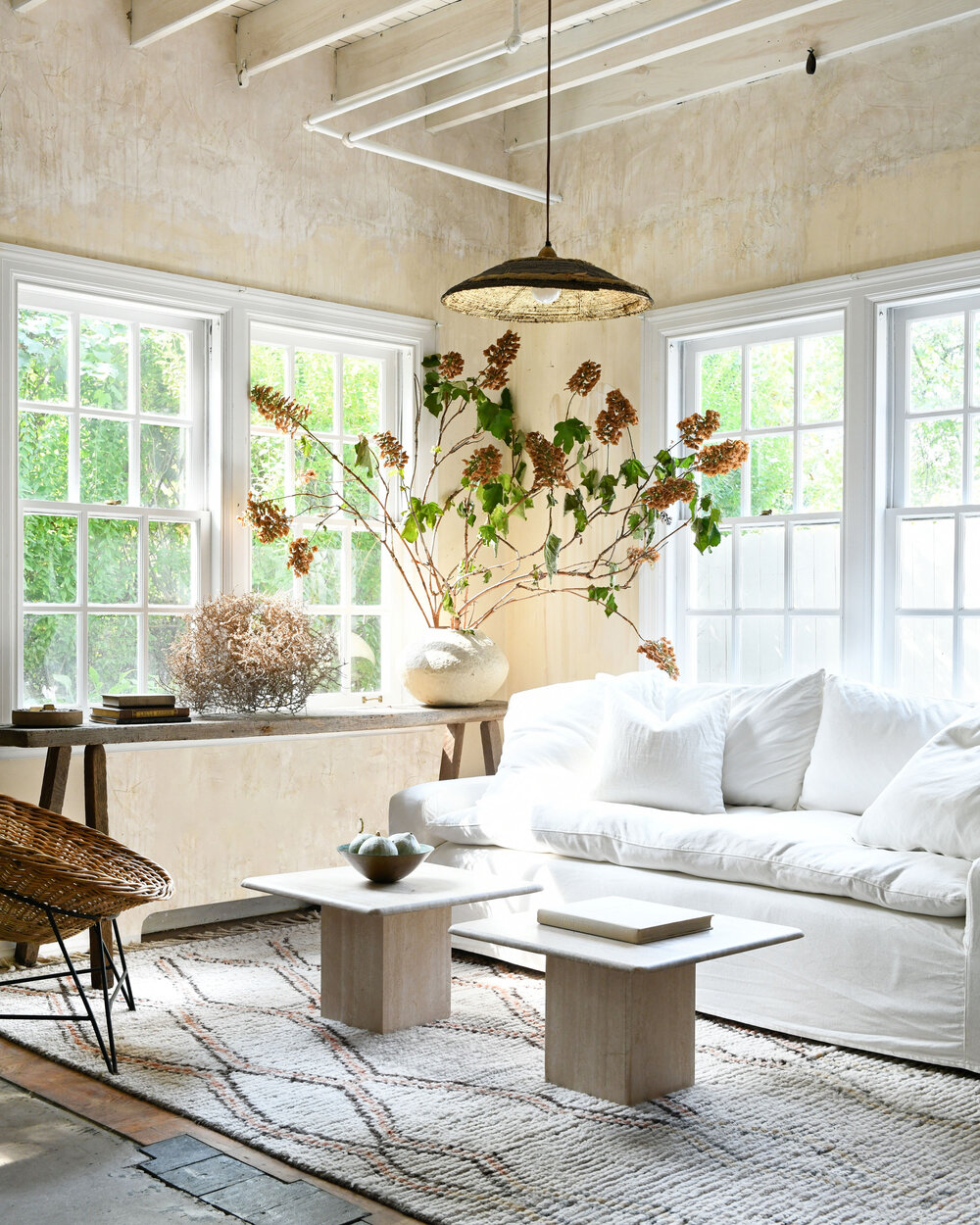 Leanne Ford designed living room with walls rubbed with coffee, a mix of pieced together flooring, white slipcovered sofa, and rustic organic modern style - photo by Erin Kelly.