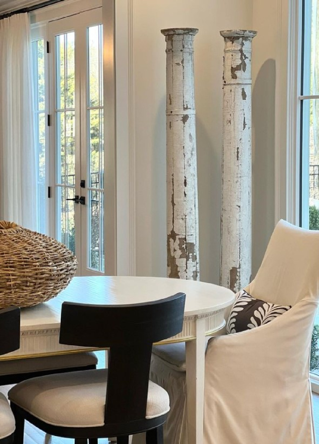 Ethereal and classic white dining room with chippy vintage columns and oval table - design by Sherry Hart.