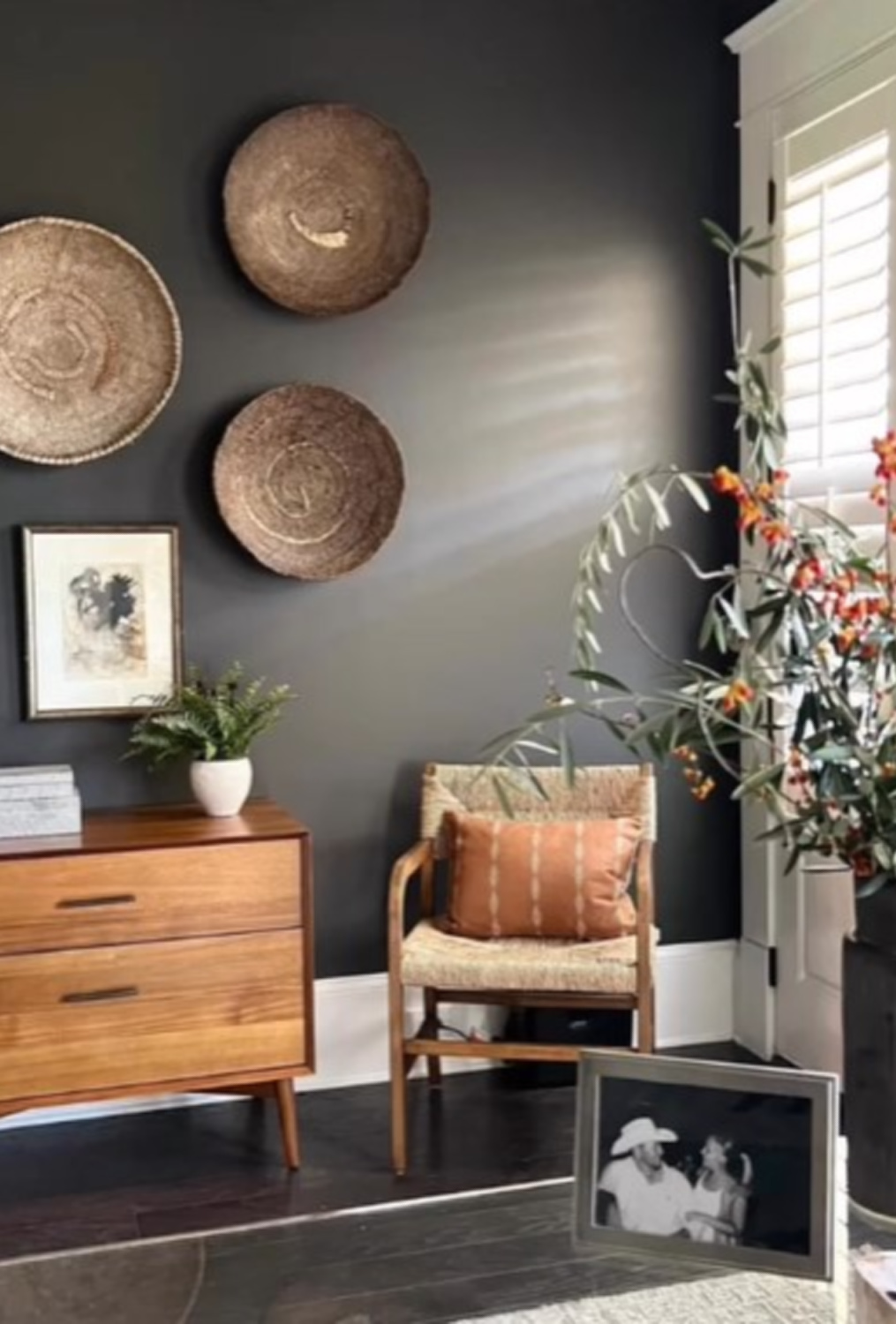 Black wall decorated with woven baskets in a home office with design by Sherry Hart.