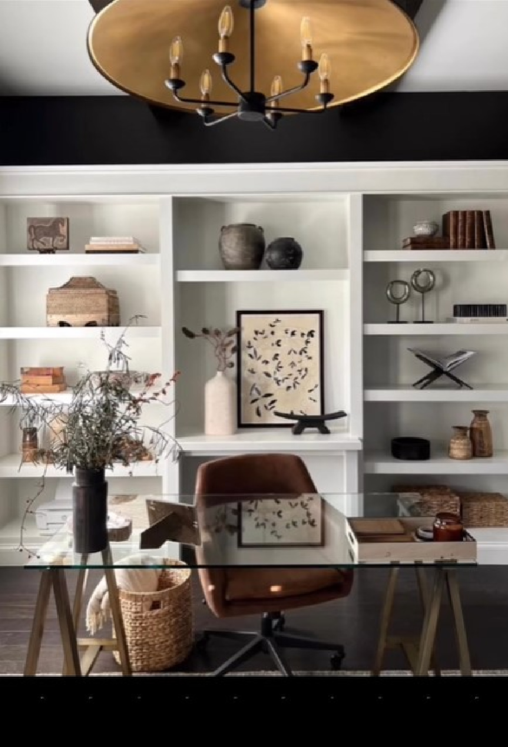 Sherry Hart designed home office with built-ins, black walls, high contrast with painted shelves and glass desk.