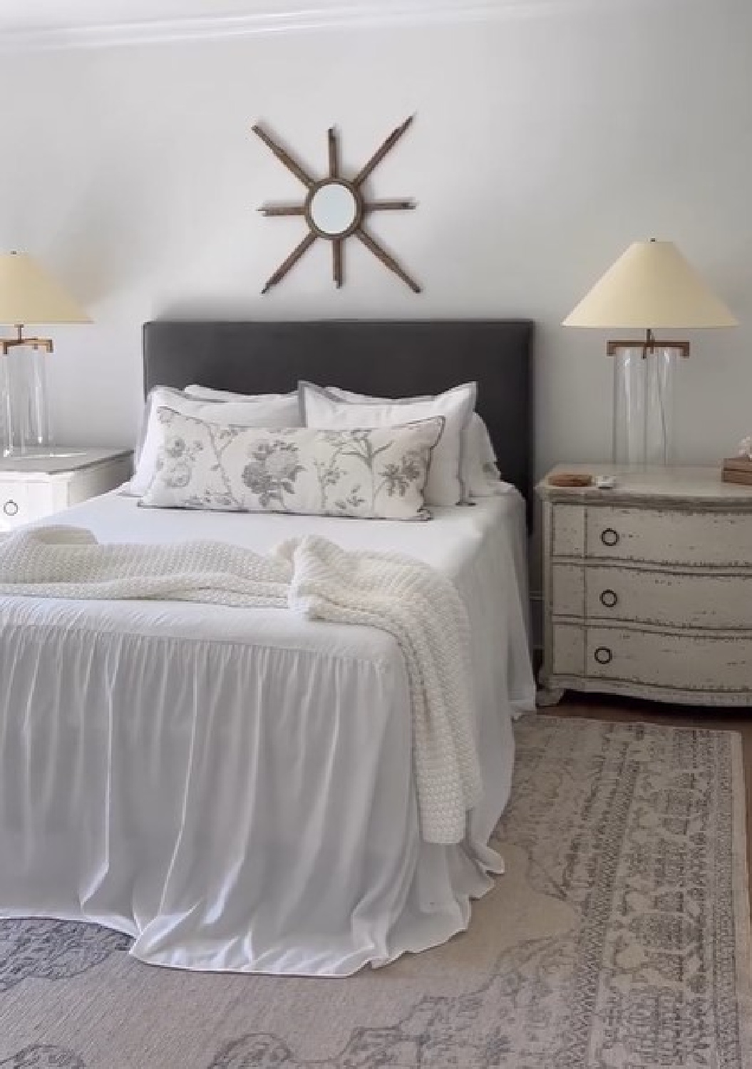 Sherry Hart designed romantic white bedroom with ruffled coverlet, velvet headboard, VC lamps, and muted area rug.