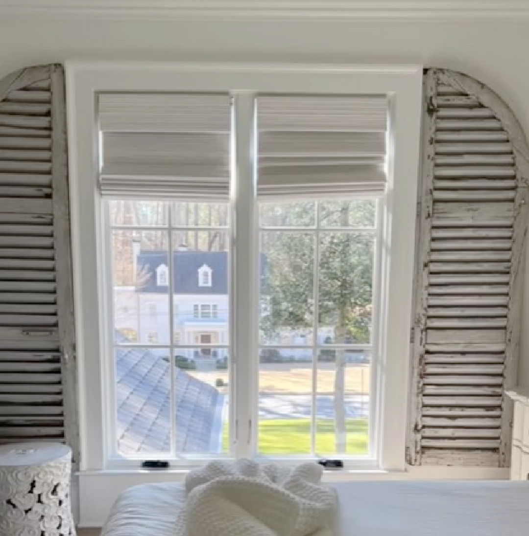 Rustic vintage arched shutters on a window in romantic bedroom designed by Sherry Hart.
