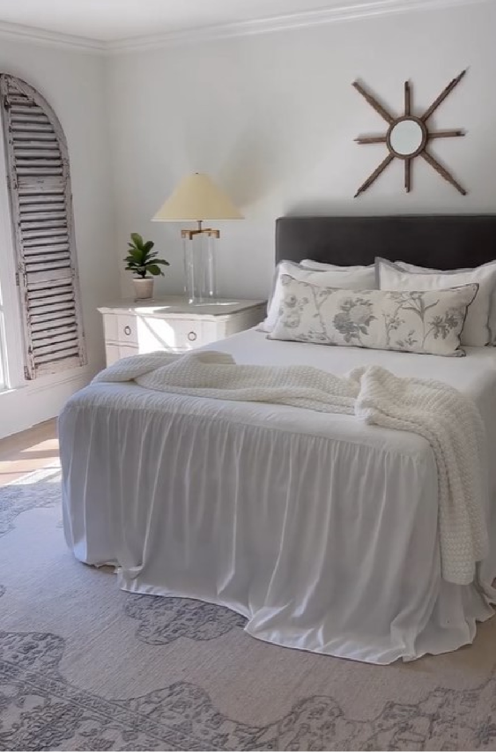 Sherry Hart designed romantic white bedroom with ruffled coverlet, velvet headboard, VC lamps, and muted area rug.