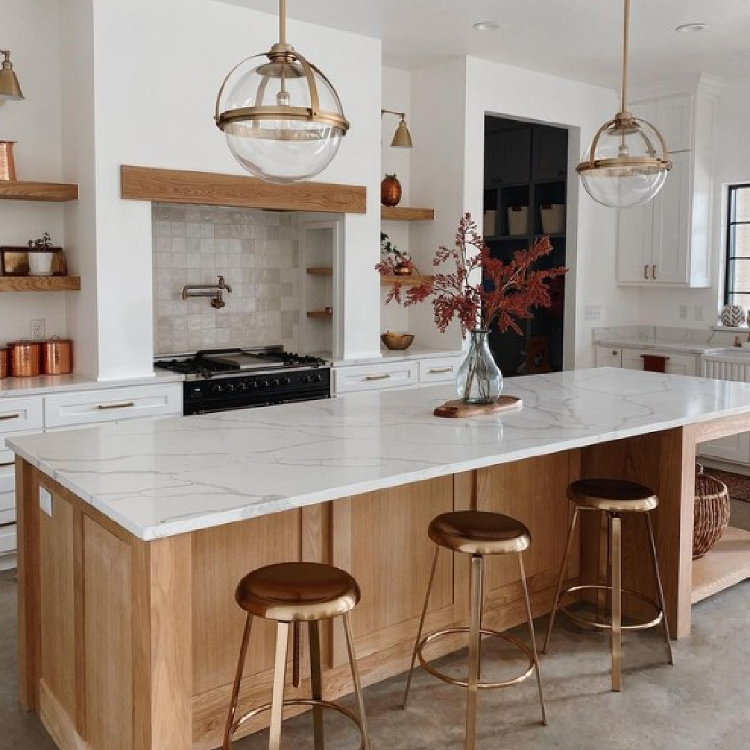 Warm modern touches in a kitchen with BM Chantilly Lace, stained wood island, concrete flooring, and sphere pendants - @archtetypedesigns. #chantillylace