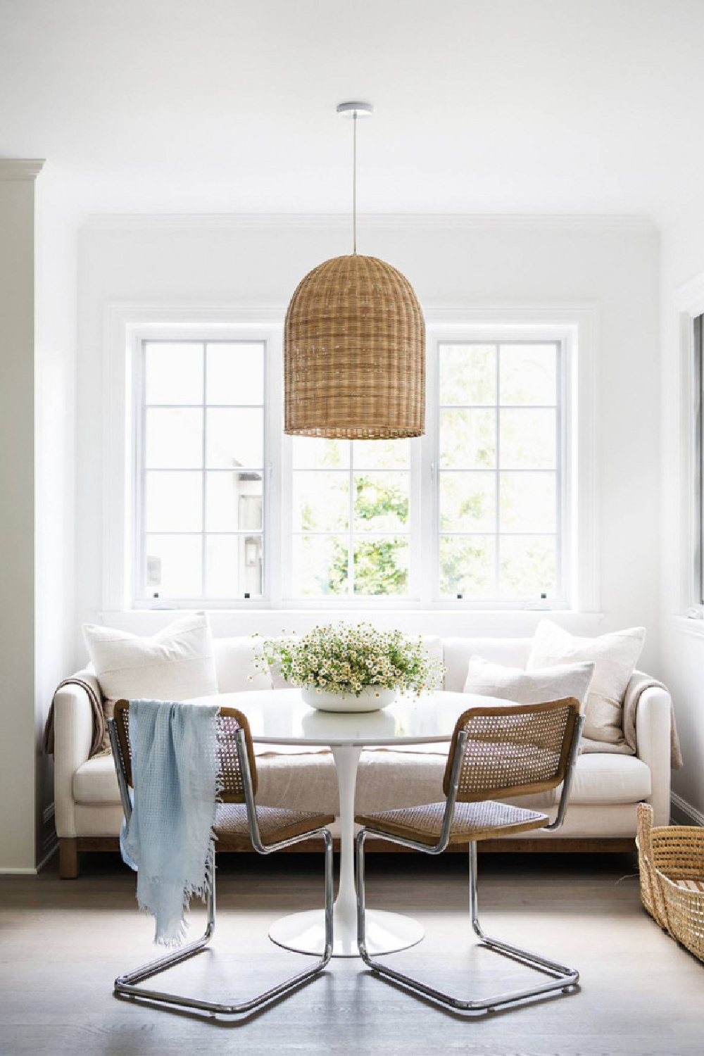 Erin Fetherston's breakfast nook with sofa, woven pendant, midcentury Marcel Breuer cane back chairs, and Chantilly Lace paint color on walls. #bmchantillylace #chantillylace