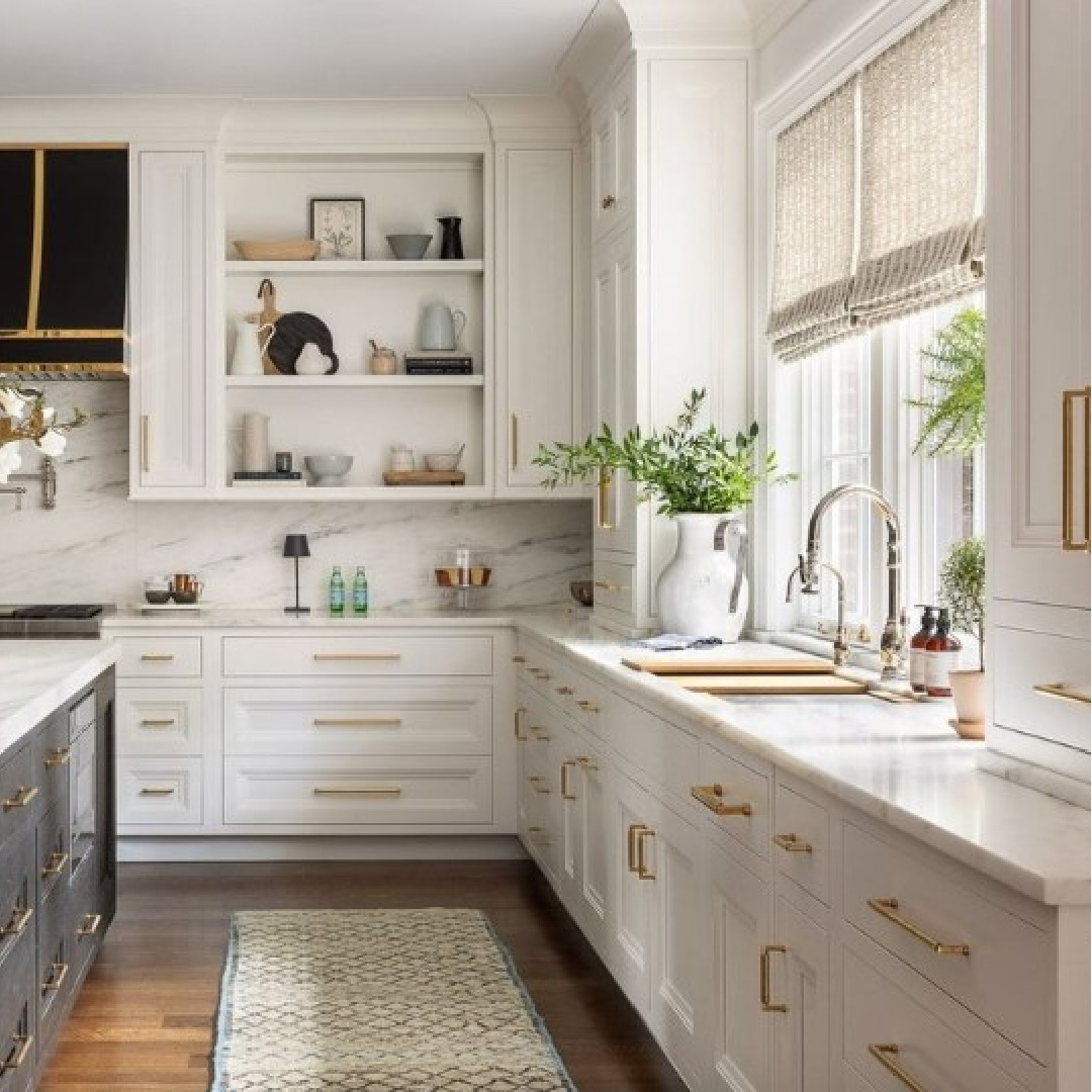 Chantilly Lace painted kitchen cabinets in a gorgeous design with black island and luxurious range hood - @Brittdesignstudio (photo by @mikevantassell)