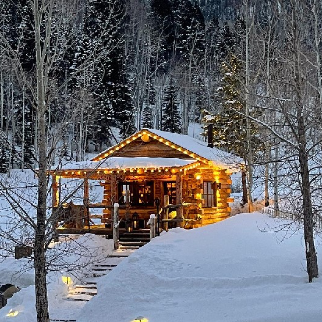 Tiny log cabin in Aspen woods in winter with white lights and charming porch - @osborninteriors. #logcabins #cabinarchitecture #cottagearchitecture