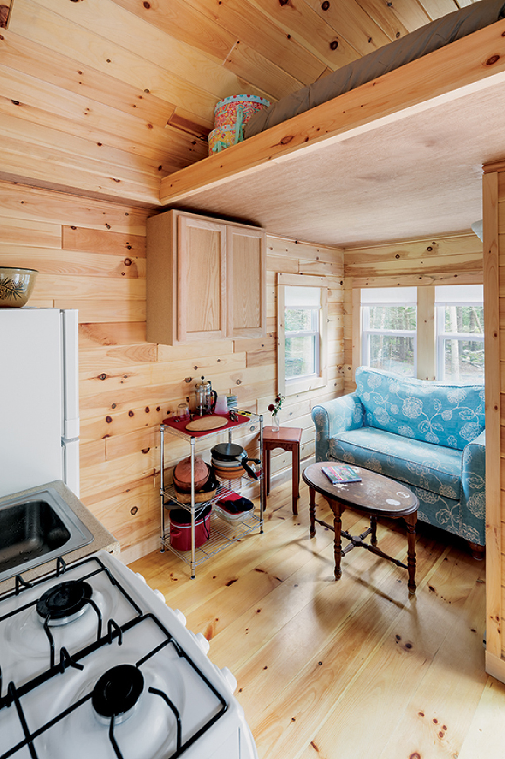 Knotty wood plank walls and ceilings in a tiny cottage kitchen and living area in Maine - @downeast. #tinyhouseinteriors #rusticpaneling
