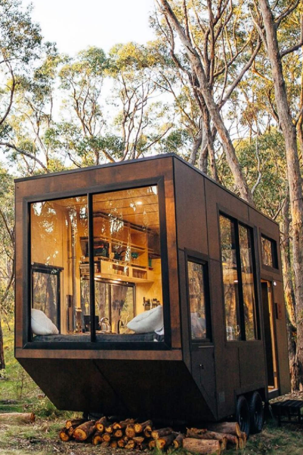 Modern mobile tiny home in woods with huge windows and modern design - @settdesign. #tinyhousearchitecture #tinyhouseexterior #moderntinyhouse