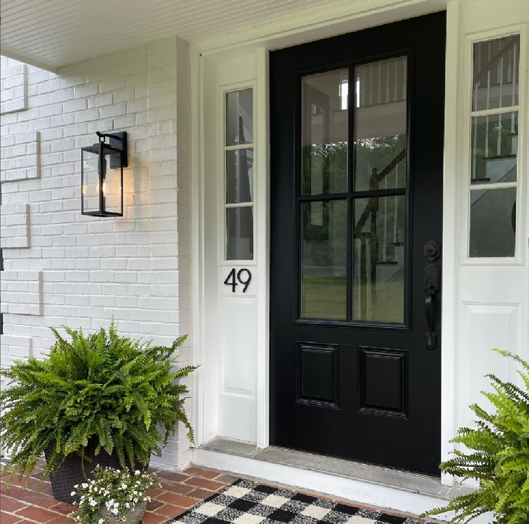 SW Eider White paint color on white brick house exterior with black door - @design_genes. #eiderwhite #whitehouseexterior