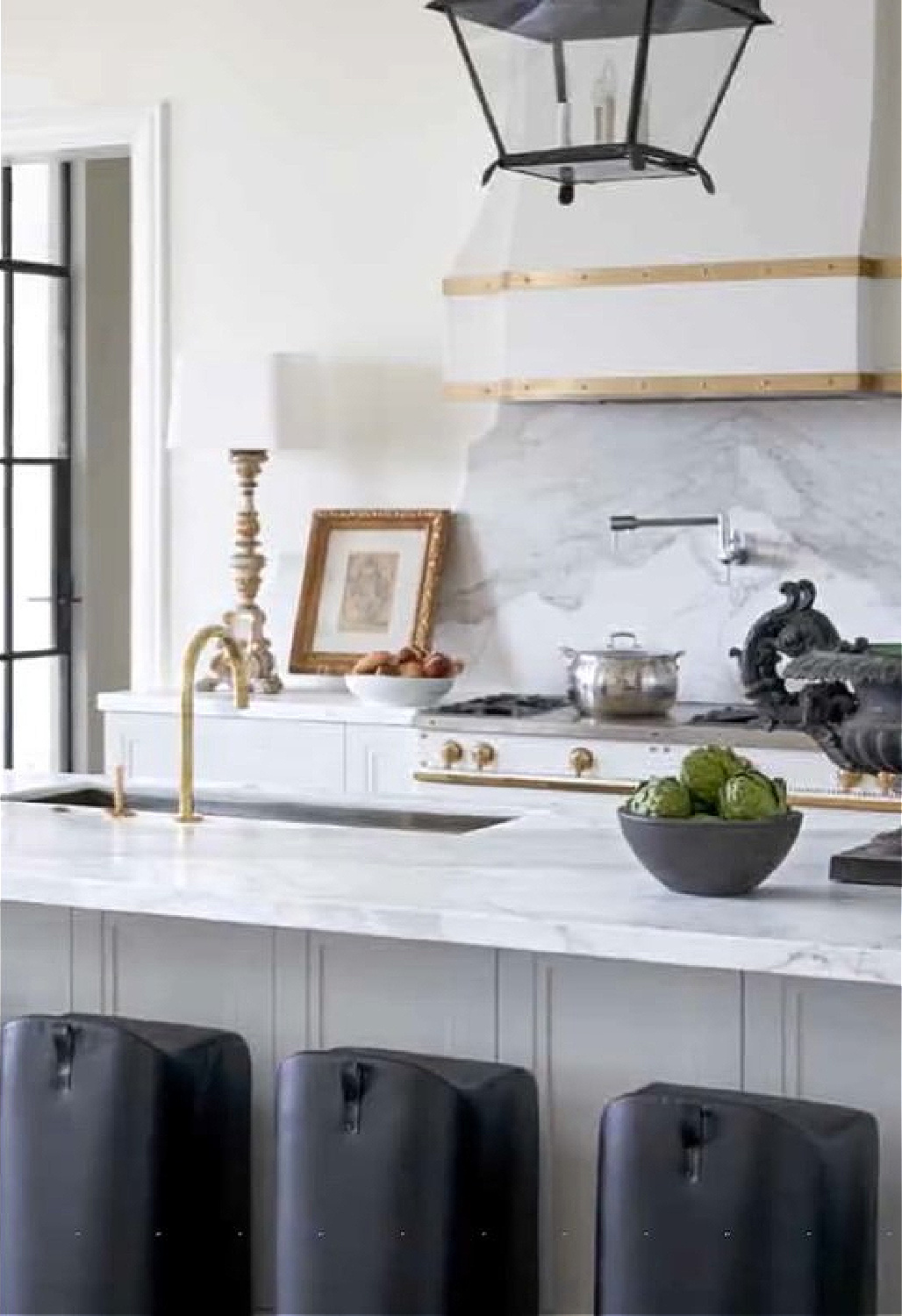 Tara Shaw designed kitchen with modern black counter stools, brass accents, antiques and white marble - @tarashawdesign.