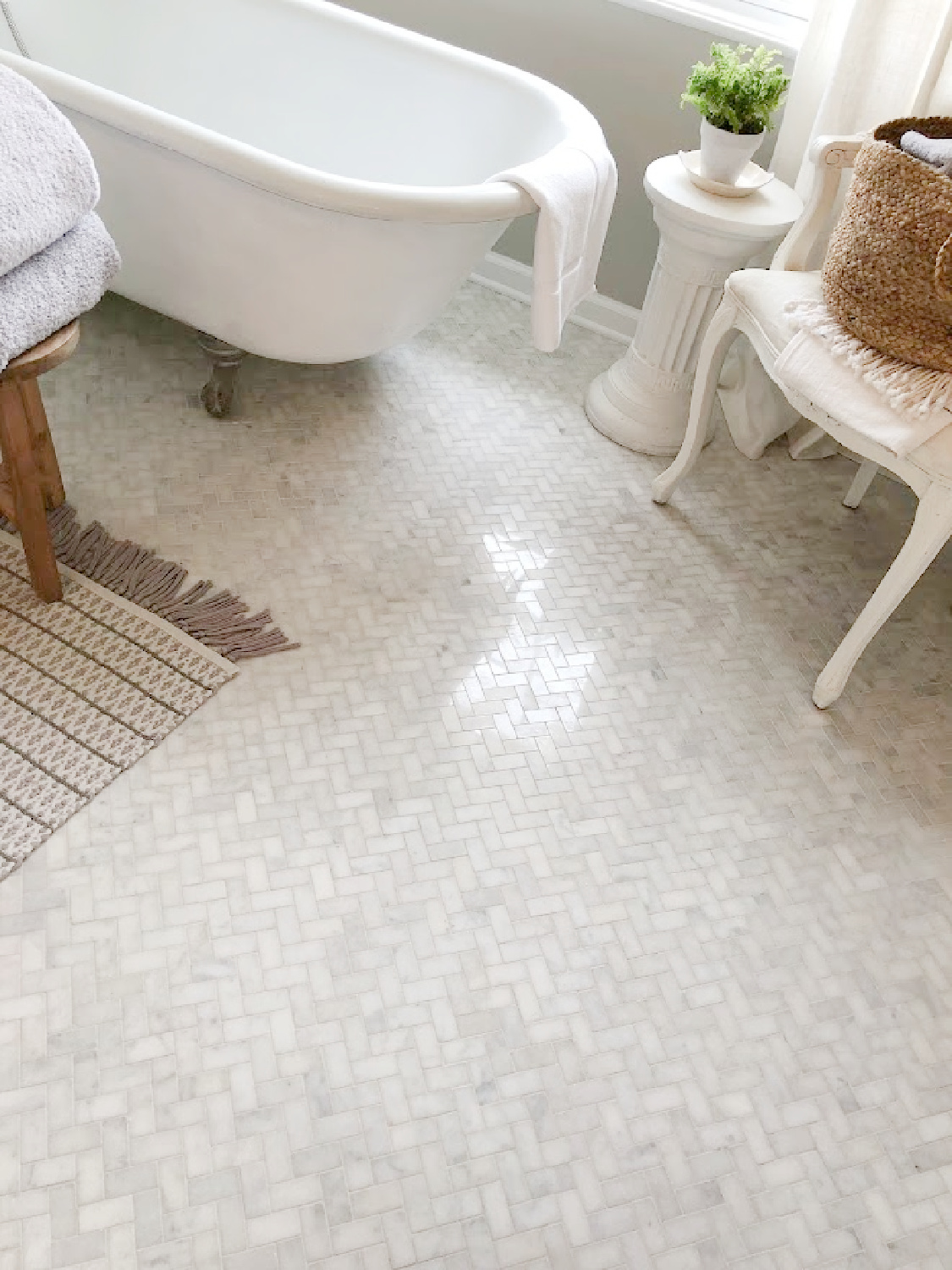 White Grecian herringbone marble mosaic tile floor, vintage clawfoot tub, and Louis chair in our modern French renovated bath at the Georgian - Hello Lovely Studio.