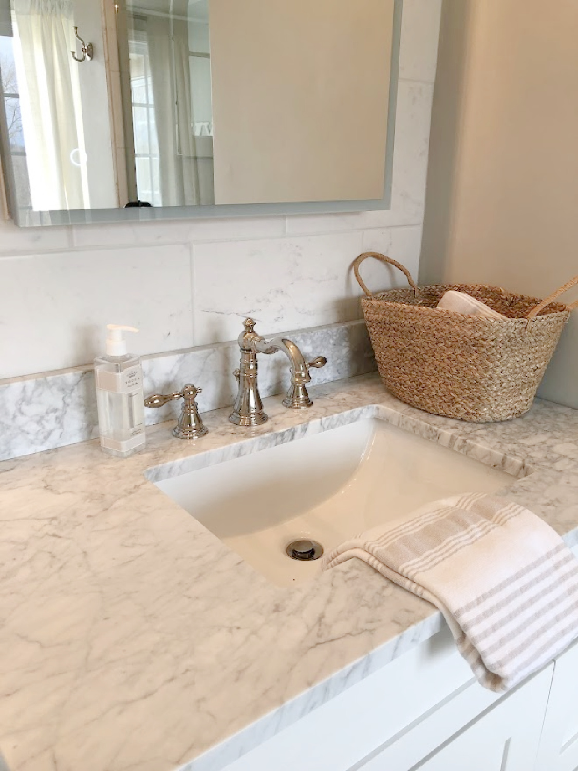 Modern LED medicine cabinet, carrera marble topped vanity, and Edwardian polished nickel faucet in our modern French renovated bath at the Georgian - Hello Lovely Studio.
