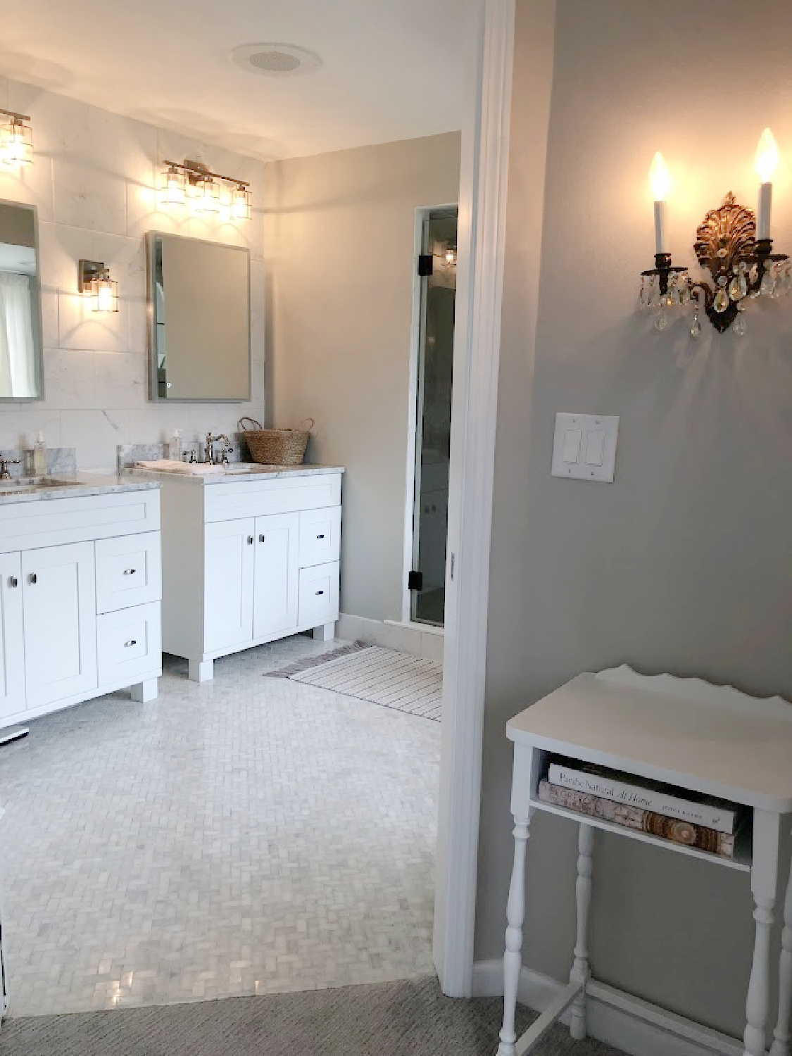 View from pocket door of vanities and herringbone marble mosaic tiled floor in our modern French renovated bath at the Georgian - Hello Lovely Studio. Walls are SW Repose Gray.