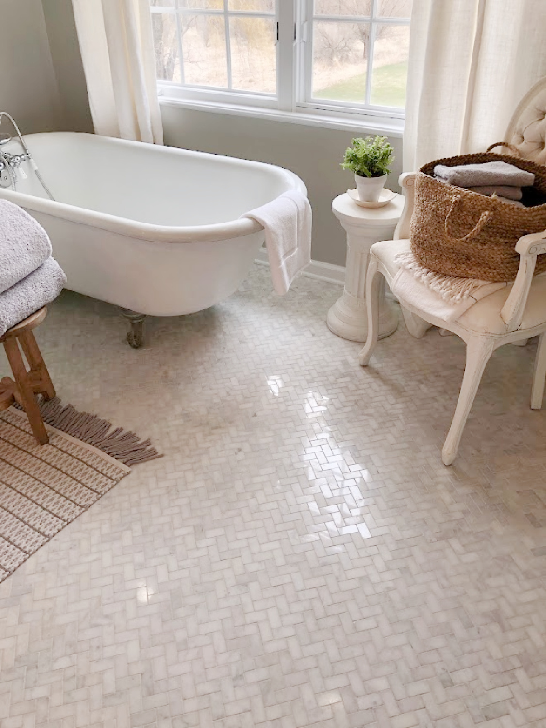 White Grecian herringbone marble mosaic tile floor, vintage clawfoot tub, and Louis chair in our modern French renovated bath at the Georgian - Hello Lovely Studio.