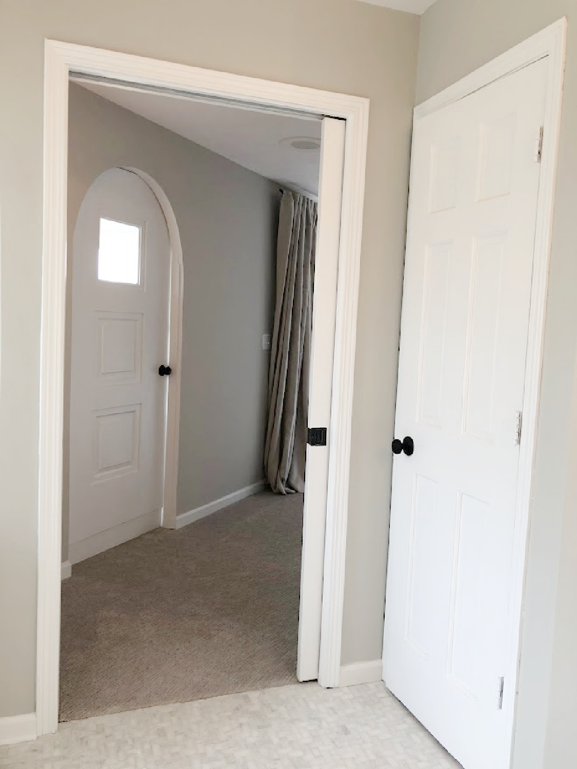 View of white painted door to WC, pocket door, and arched door to sitting room in our renovated suite at the Georgian - Hello Lovely Studio.