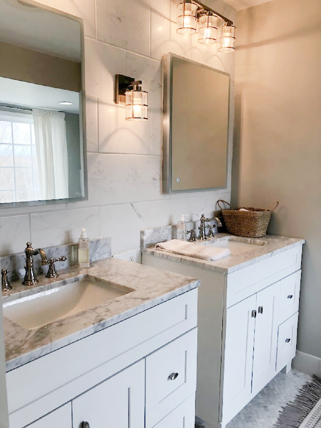 Shaker style white vanities with marble tops, lantern sconce, modern LED medicine cabinets, and SW Repose Gray on wall in modern French renovated bath at the Georgian - Hello Lovely Studio.
