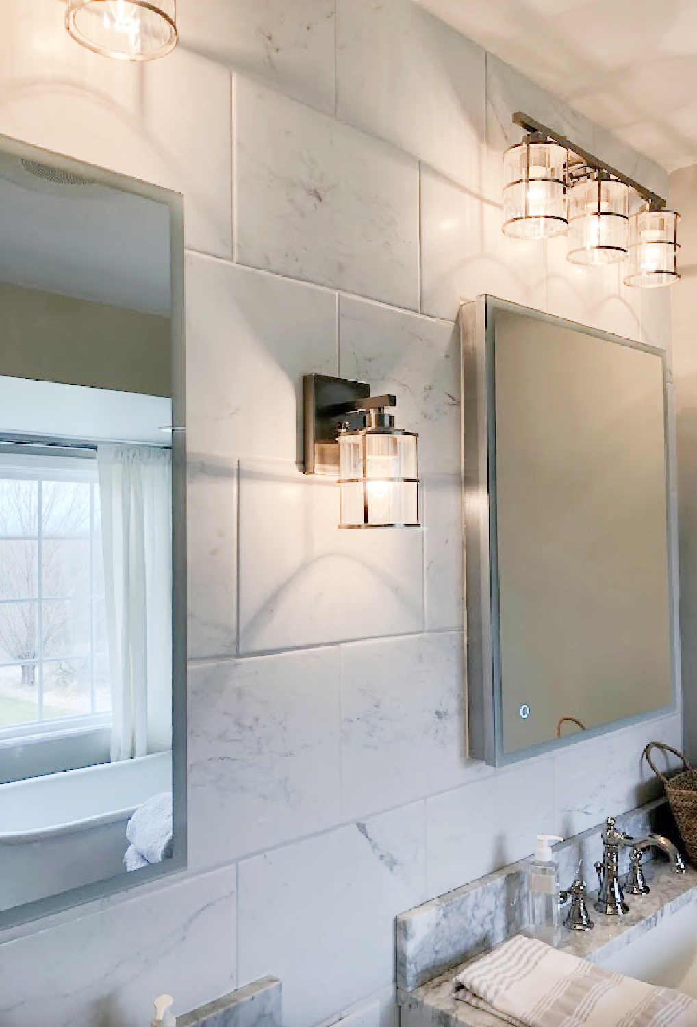 Lantern style vanity lighting on marble look porcelain tiled wall with modern LED medicine cabinets over Shaker style vanities with marble tops - modern French bath renovation at the Georgian by Hello Lovely Studio.