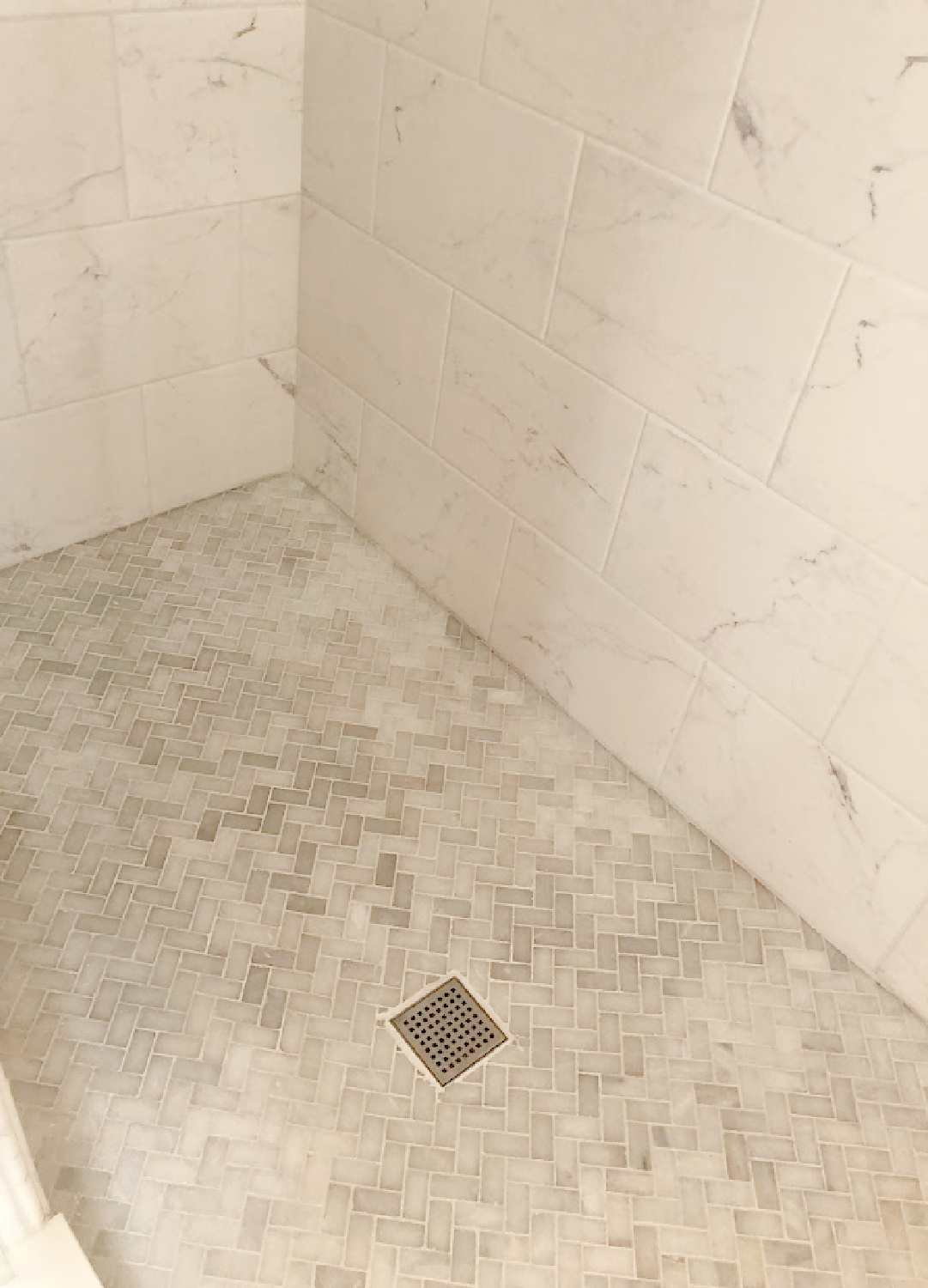 Detail of Grecian white marble mosaic herringbone tiled shower floor and marble look porcelain wall tile - Hello Lovely Studio.