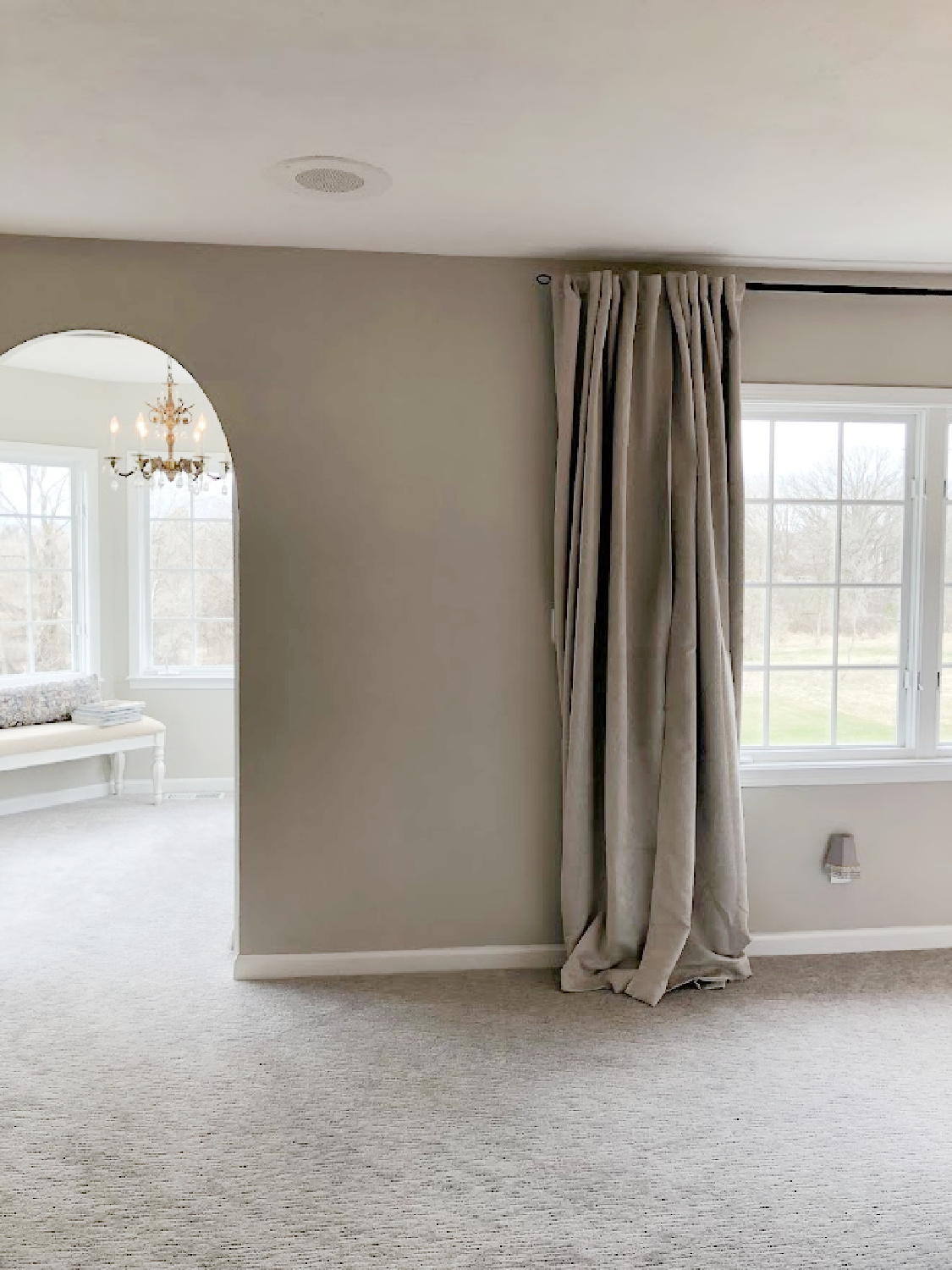 Arched doorway to sitting room in coastal bedroom remodel (SW Agreeable Gray on walls) at the Georgian - Hello Lovely Studio. #agreeablegray #swagreeablegray