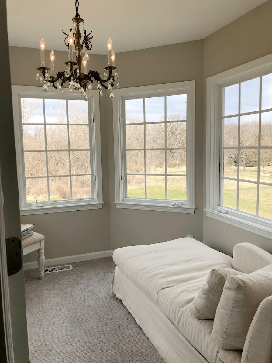 Belgian linen chaise in turret designed sitting room in coastal bedroom remodel (SW Agreeable Gray on walls) at the Georgian - Hello Lovely Studio. #agreeablegray #swagreeablegray