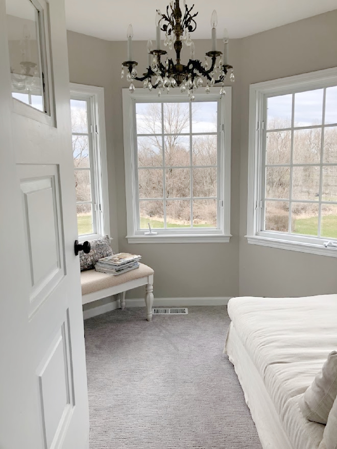 Vintage exterior door open to turret sitting room with linen chaise and bench in coastal bedroom remodel (SW Agreeable Gray on walls) at the Georgian - Hello Lovely Studio. #agreeablegray #swagreeablegray