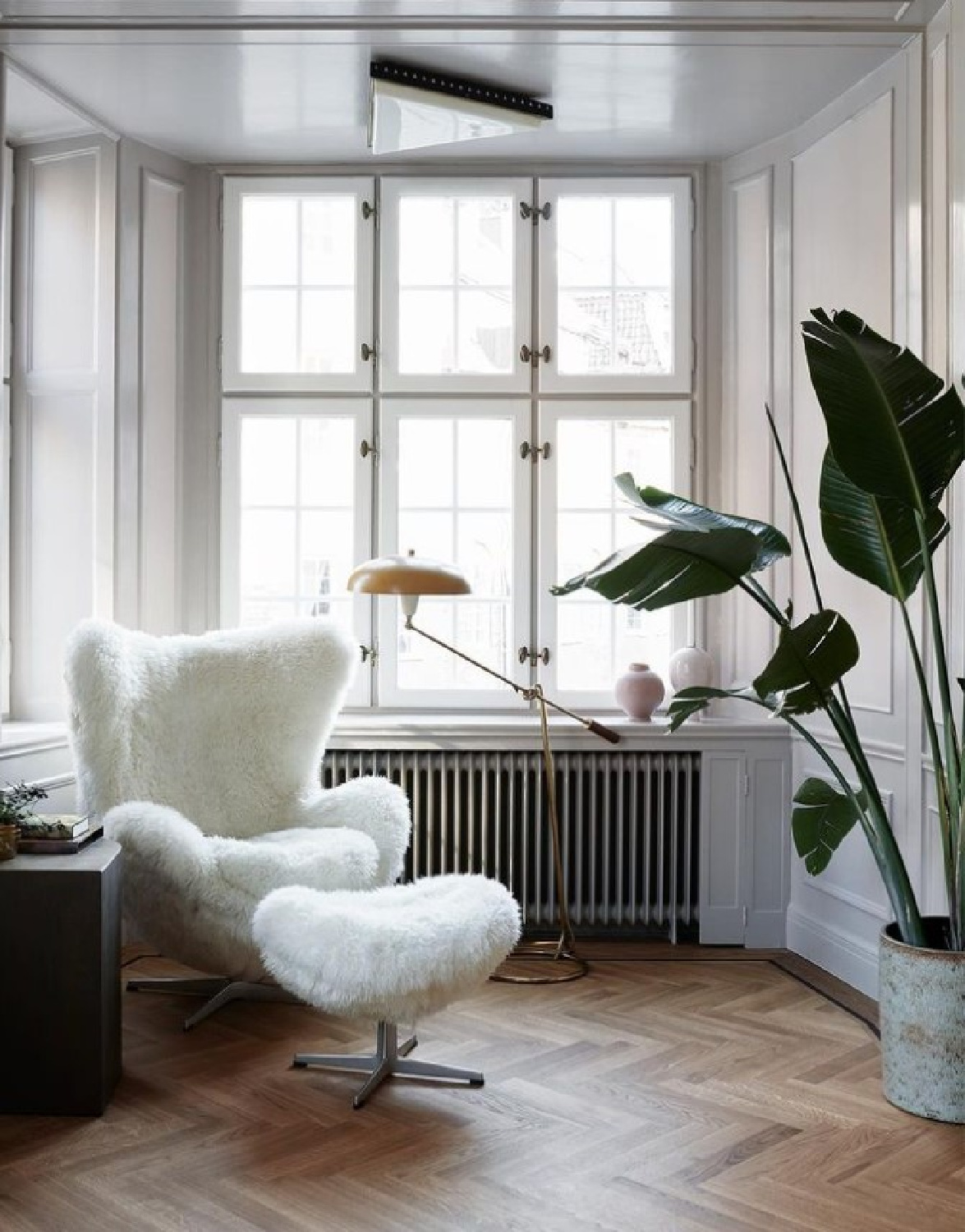 Shearling covered modern egg chair and ottoman in a sunny corner of a Stockholm apartment - @elledecorationfr #stockholmapartment #eggchairs