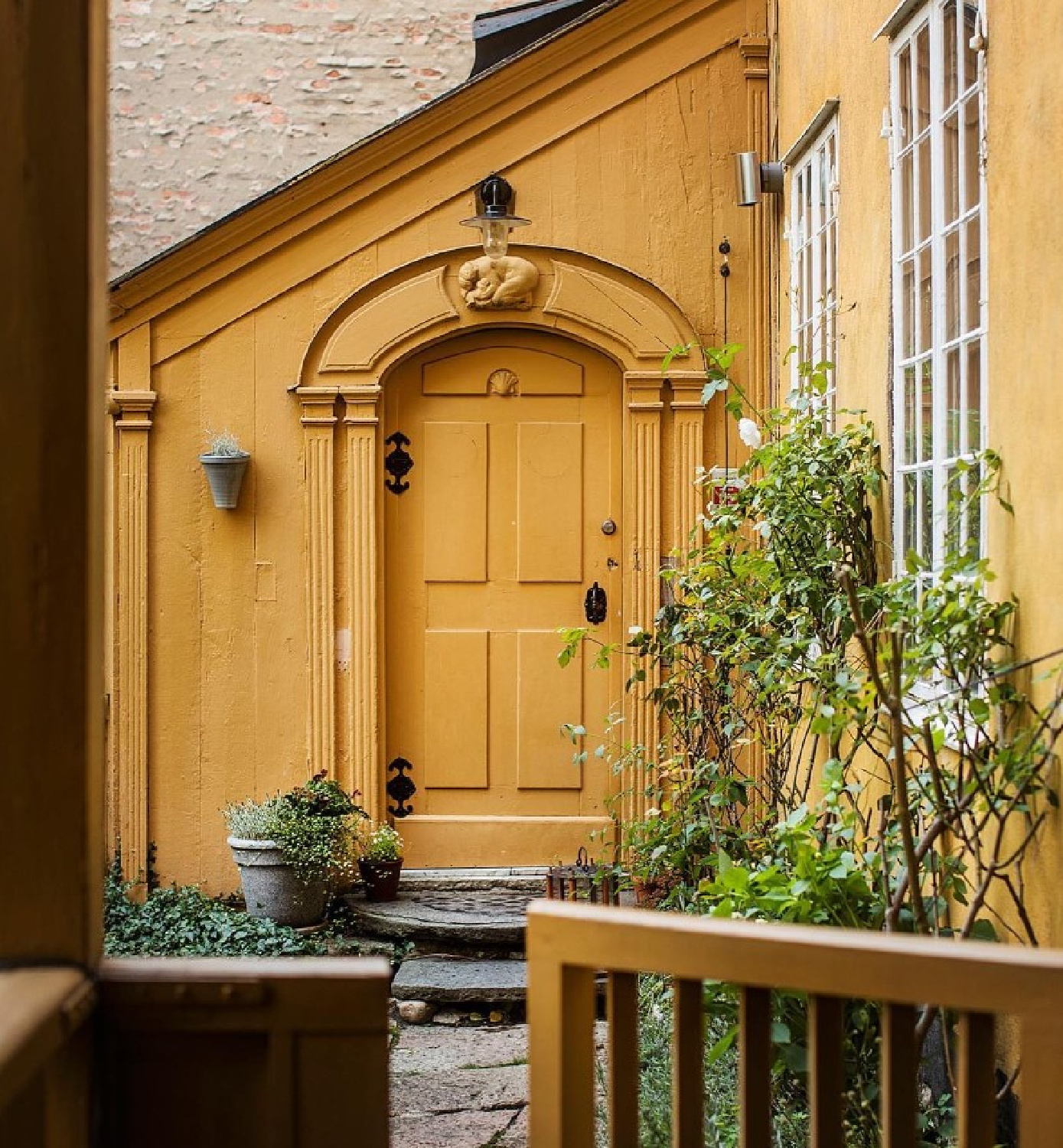 Bold and beautiful ochre exterior and arched door of a breathtaking Stockholm apartment - @historiskahem. #stockholmapartment #stockholmexterior