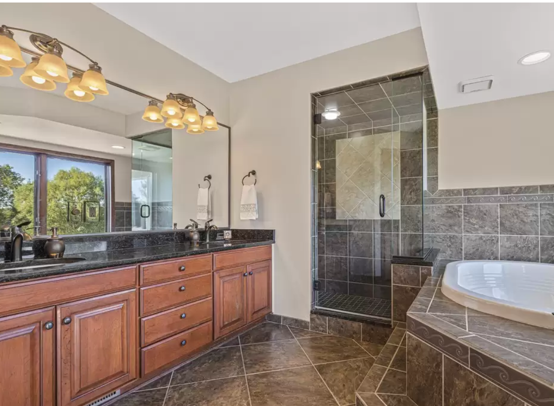 BEFORE bath with cherrywood vanity, brown granite, brown tiled walk-in shower, and tiled platform with Jacuzzi tub - Hello Lovely Studio