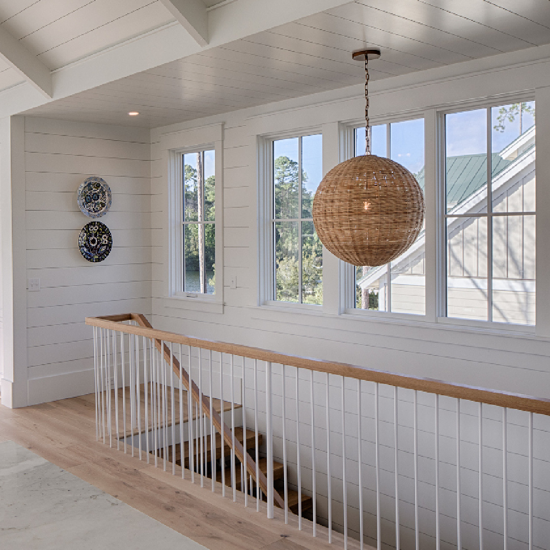 Staircase with rattan globe chandelier in a board and batten coastal cottage in Palmetto Bluff. Modern farmhouse interior design by Lisa Furey. #shiplap #staircase #coastalcottage #interiordesign