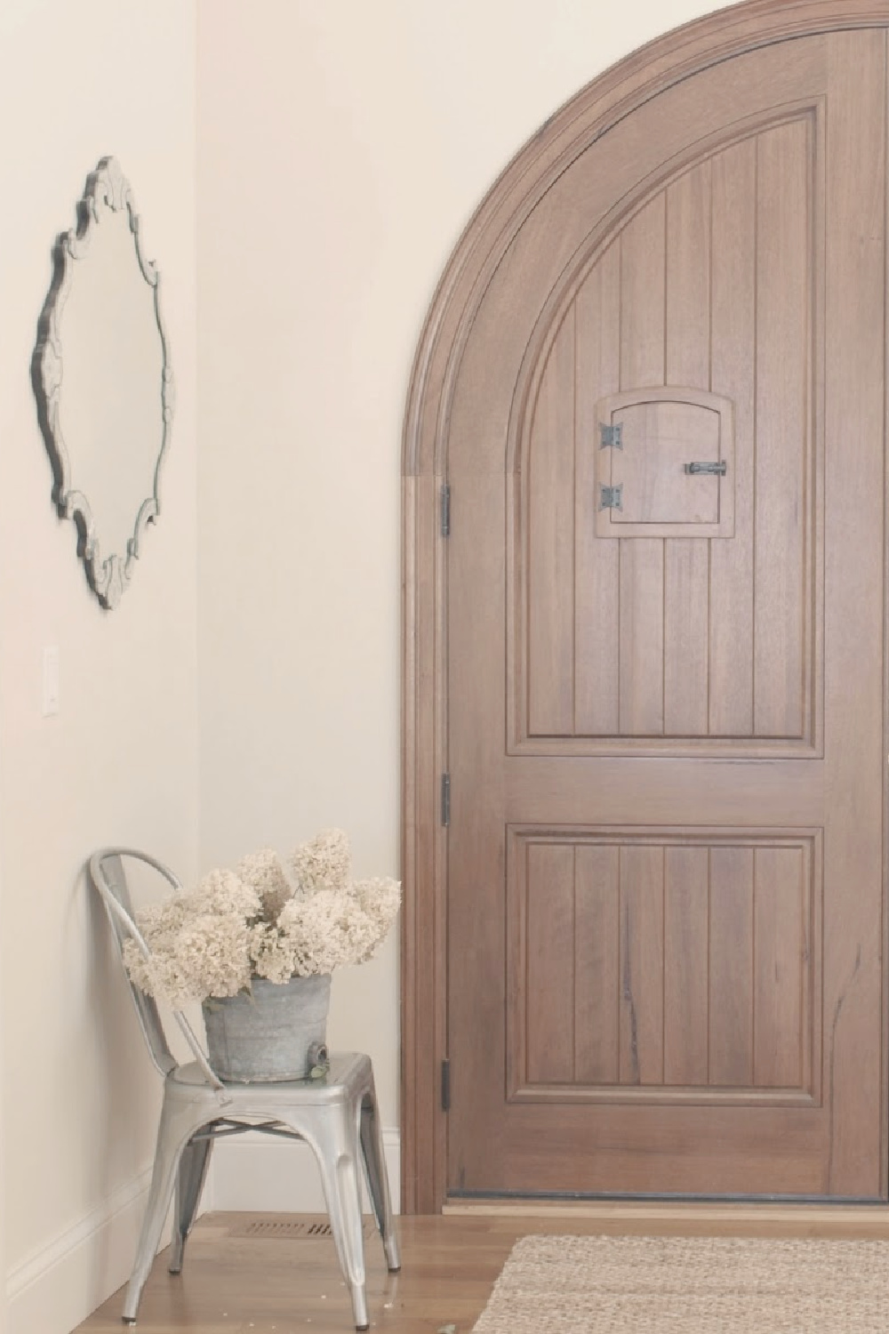 BM White Sand in a modern French entry hall with arched walnut front doors - Hello Lovely Studio. #bmwhitesand