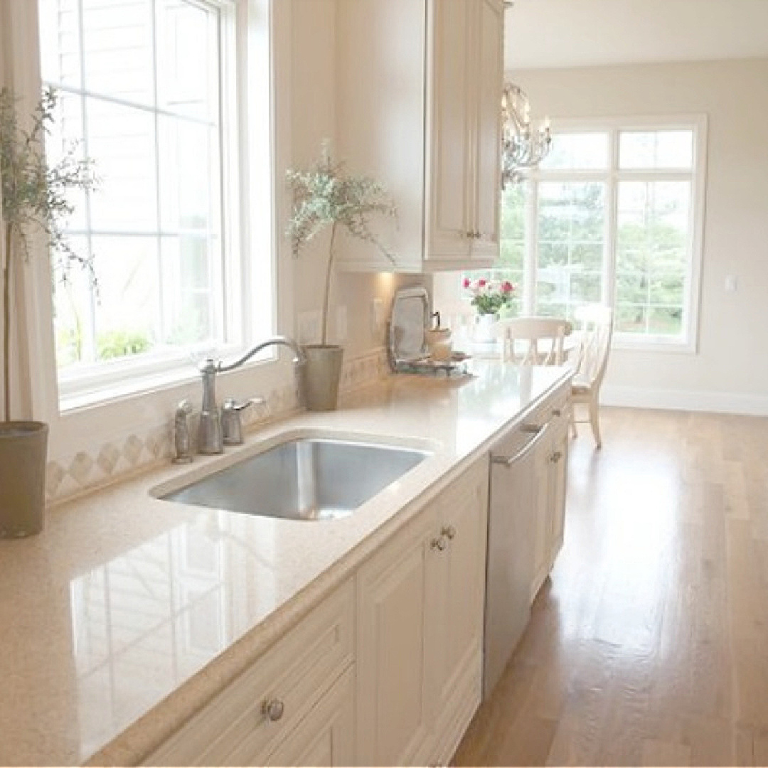 White Sand (Benjamin Moore) in my French country kitchen with Silestone Ivory Coast counters, warm white Thomasville cabinets, and white oak hardwood flooring - Hello Lovely Studio. #bmwhitesand #hellolovely #frenchkitchens