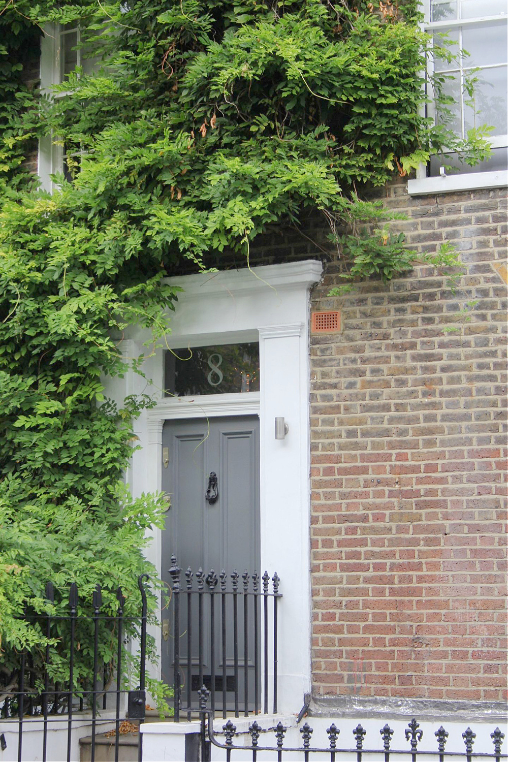Beautiful sophisticated gray door and brick row house exterior in Notting Hill. Come explore paint colors for your front door. #frontdoorcolors #paintcolors #curbappeal