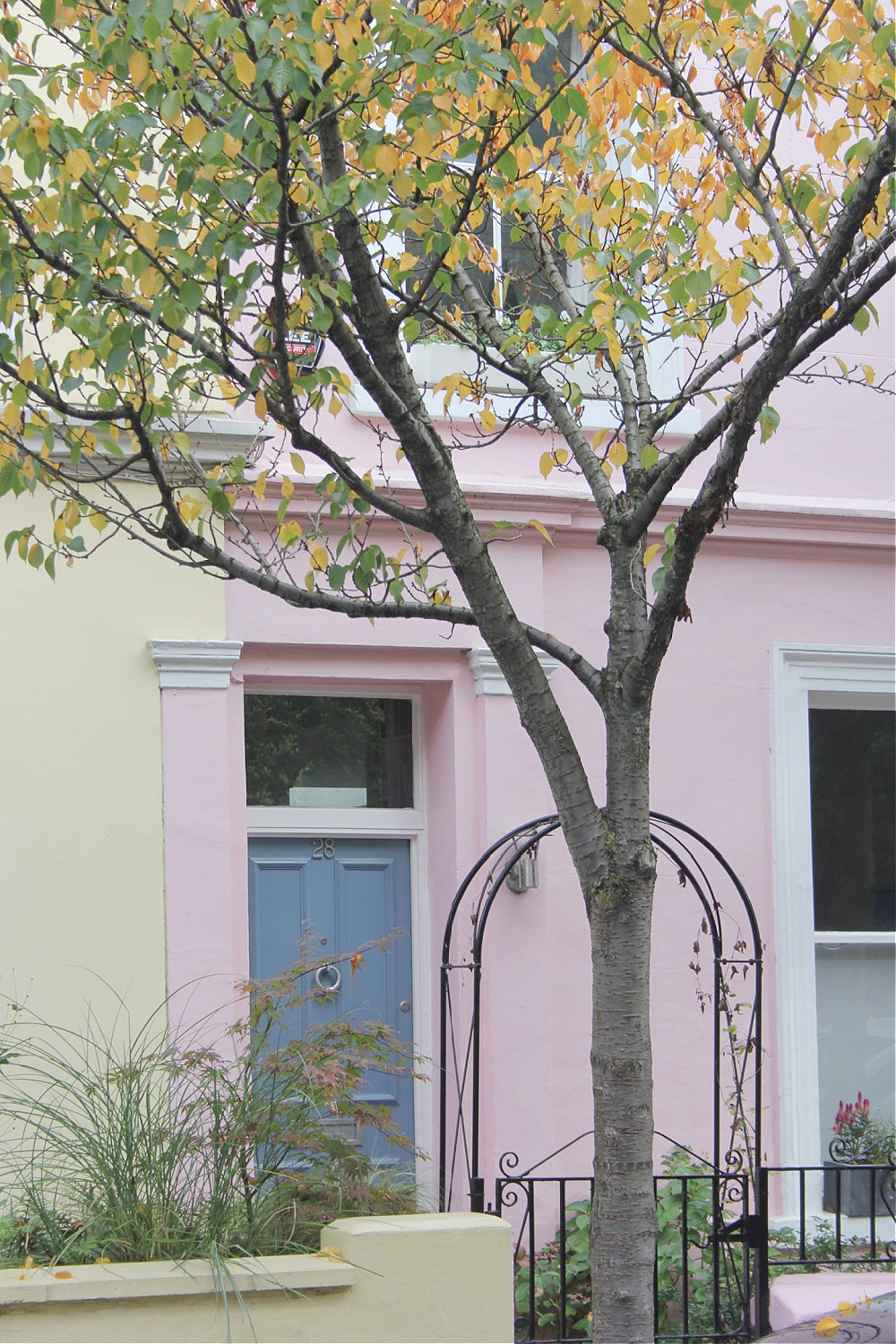 Swedish blue front door on yellow and pastel pink row house in Notting Hill. Come explore paint colors for your front door. #frontdoorcolors #paintcolors #curbappeal