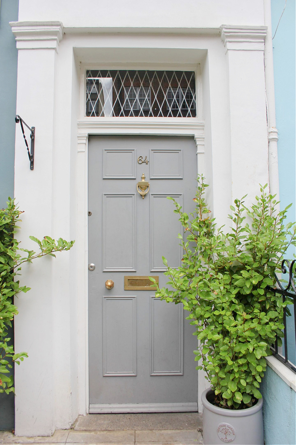 Sophisticated grey front door on white house in Notting Hill. Come explore paint colors for your front door. #frontdoorcolors #paintcolors #curbappeal