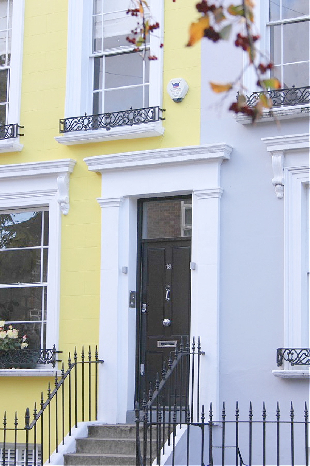 Gorgeous black door with white trim on vibrant yellow row house in Notting Hill. Come explore paint colors for your front door. #frontdoorcolors #paintcolors #curbappeal